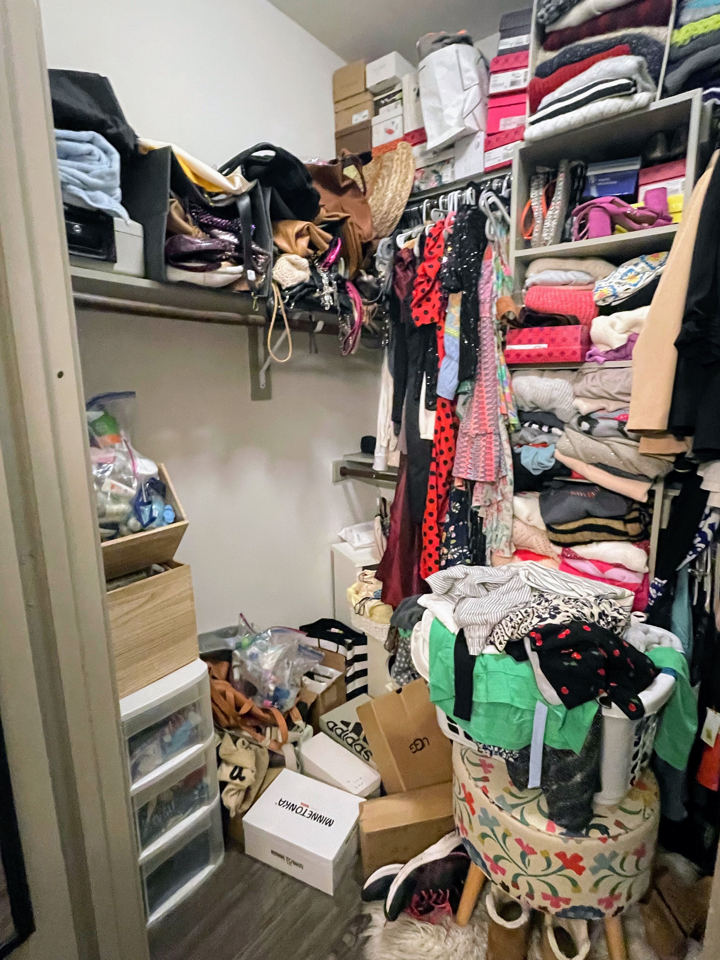 Overstuffed closet with clothes piled on a stool and floor